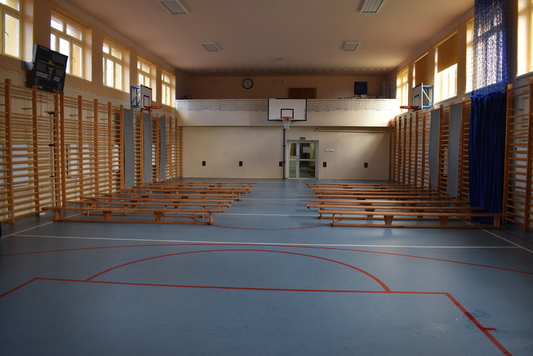 Widok na zmodernizowaną salę gimnastyczną z ustawionymi w dwóch rzędach ławkami.