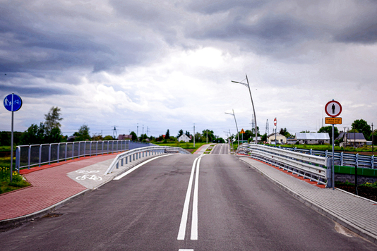 Dwupasmowa droga asfaltowa wiodąca przez most. 