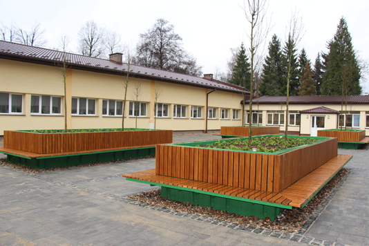 szkolny dziedziniec z klombami roślinności
